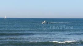 A small motorboat sails off the coast of Lido di Ostia in calm seas on a clear morning with a clear sky in Rome.