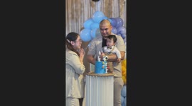 Baby confused by his first birthday cake grasps candle and cries