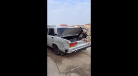 Person pushes out car dent with legs from inside boot