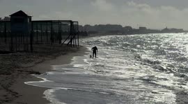 A metal prospector, against the light, searches for precious objects along the beach of Lido di Ostia on a beautiful March day in Rome.