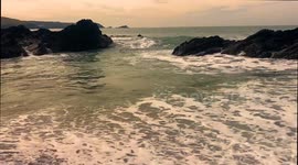 UK Travel, Waves slowly pound the shingle on a deserted idyllic sea cove, Nun Cove, Newquay, Cornwall, UK