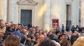 A transgender woman holds up a sign with some photos and movie covers and the words 'goodbye Eleonora' outside the Church of the Artists during the funeral of Italian actress Eleonora Giorgi in Rome.