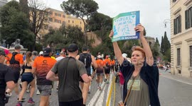 A woman holds up a sign with the slogan ‘My laurel go, go, go’ and little hearts as she searches for someone among the runners passing by during the Acea Run Rome The Marathon in Rome.