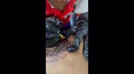 Schoolboy, nine, tattoos elaborate dragon design on a relative's back