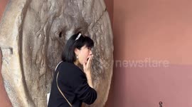 Tourists take souvenir photos in front of the Mouth of Truth in Rome.