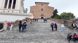 Tourists ascend and descend the Ara Coeli Staircase on a cloudy day in March in Rome.