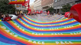 Protesters carry a large banner with the colors and words 'peace' and wave flags of the Communist Refoundation Party during the demonstration to say no to rearmament called by left wing movements in Rome.