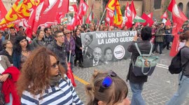 Protesters march behind the Potere al Popolo banner with photos of European leaders and the slogan 'not one euro for their war' during the demonstration to say no to rearmament called by left wing movements in Rome.