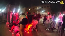 Women roll around the floor fighting in front of shocked police officers
