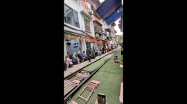 Tourists in awe as train steams through Hanoi market just INCHES away from them