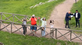 Tourists with immersive headsets with see-through augmented and virtual reality technology take a virtual tour of Ancient Rome and zoom out for a wide shot with Circus Maximus in the background in Rome.