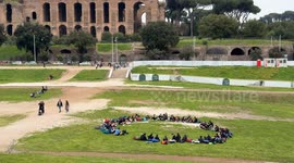 Some young scouts have a picnic sitting in a circle in the area of the Circus Maximus in Rome.