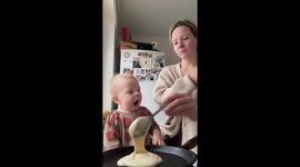 Toddler excitedly flips pancake while cooking breakfast in Moscow, Russia