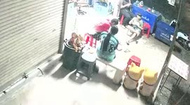 Snake slithers under woman's chair as she sits outside shop
