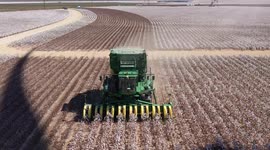 Cotton stripper harvesting in rural west Texas fields in the shadow of wind turbines