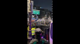 Protestors gather in large numbers in the streets of Seoul, South Korea (portrait video). Flags are waved in sync as loud music plays.