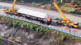Bungling crane operators drop lorry... sending it toppling down hillside