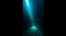 Diver descends into flooded cave only illuminated by sunbeam