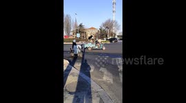 Dog balances on scooter being transported on back of owner's tricycle