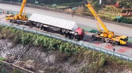 Bungling crane operators drop lorry... sending it toppling down hillside