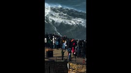 Surfer rides massive wave as spectators watch in Nazaré, Portugal