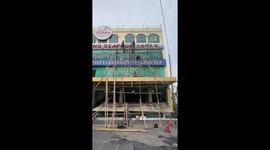 Builders repair building using bamboo poles as scaffolding