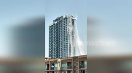 Swimming pool water cascades from apartment block roof in earthquake