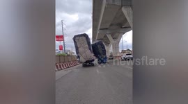 Overloaded trucks tilt dangerously along road in Thailand