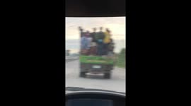 Overloaded truck carries dozens of workers on its back