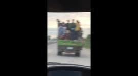Overloaded truck carries dozens of workers on its back