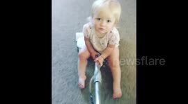Toddler sits on a vacuum while mother cleans