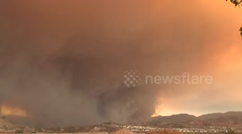 Huge tornado-like smoke plume looms over houses at