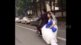Groom doesn't notice his bride fall off the back of their wedding scooter