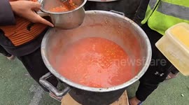 Displaced Palestinians receive hot meals distributed by aid organization in Gaza