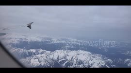From 30,000 feet just after sunset, jet descends through the clouds revealing a snow-capped Pacific Northwest mountain scape.