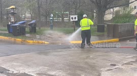 City workers use pressurized water to clean up remnants of historic flood