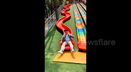 Man nails silky-smooth ride down S-shaped slide—turns hesitation into pure amusement park Joy