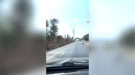 Towering dust devil tornado spins along roadside