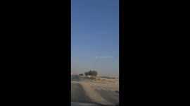 Camels which compete in racing competitions in Qatar cross the road helped by trainers