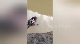 Woman found sitting on crashed overturned car in river