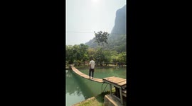Tourist falls from wooden bridge over pond in Laos