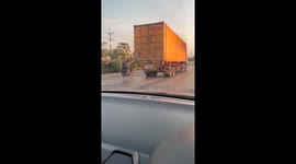 Cyclist rides behind truck in Thailand