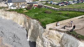 Vistors to Birling Gap, UK  walk close to the edge of the crumbling cliffs