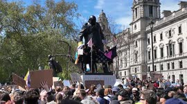 Trans protesters scale the statue of Winston Churchill in Westminster as crowds pour into Parliament Square.