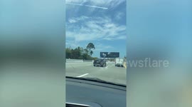 Stray wheel rolls on road alongside cars at motorway