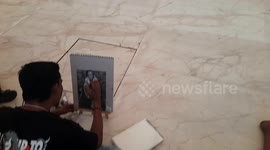 The young man is sitting at the centenary pavilion of the Shri Saibaba Samadhi in Shirdi and drawing a photo of Shirdi Sathya Sai Baba with the help of a pencil.
