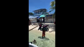 Person carries motorbike on shoulders from boat in Philippines