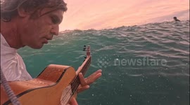 Person plays music while surfing in Lombok, Indonesia