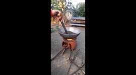 An Indian woman lights a fire in a clay oven and roasts chickpeas in a cauldron.