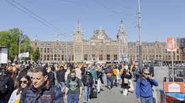 Crowds of people walking in Amsterdam with the Central railway station in the background